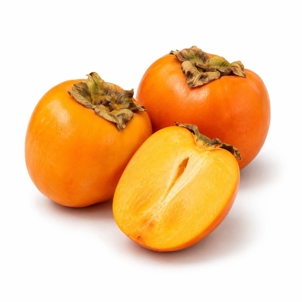 Dva cela oranžna kakija persimon in vzdolžno prerezana polovica v ospredju.