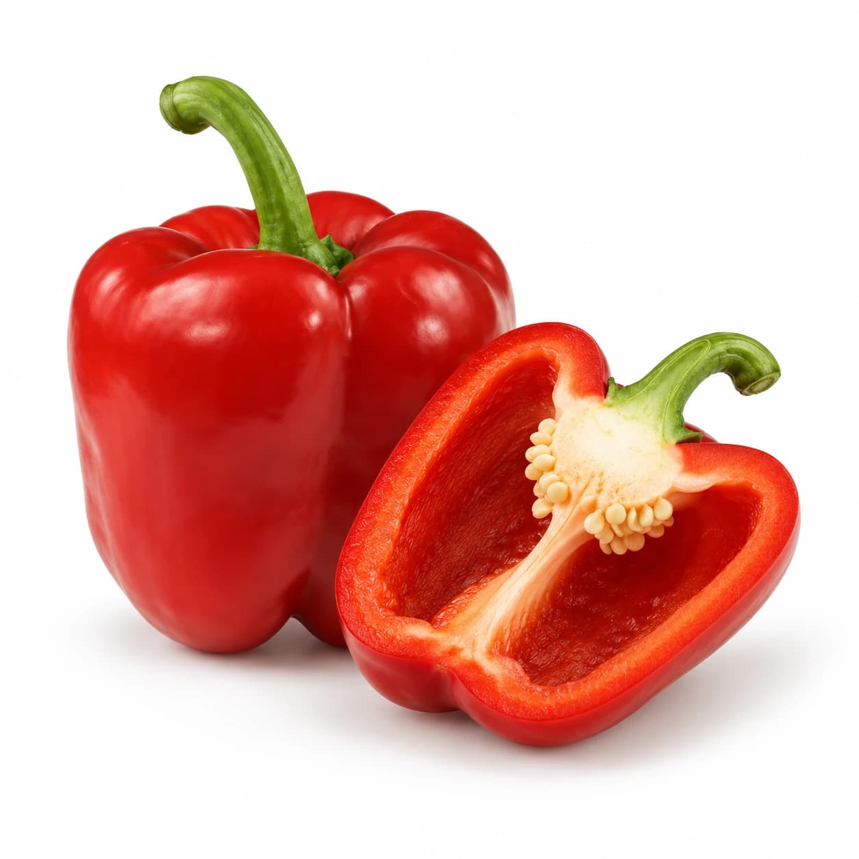 Cela rdeča paprika z zelenim pecljem in prerezana polovica s svetlimi semeni.