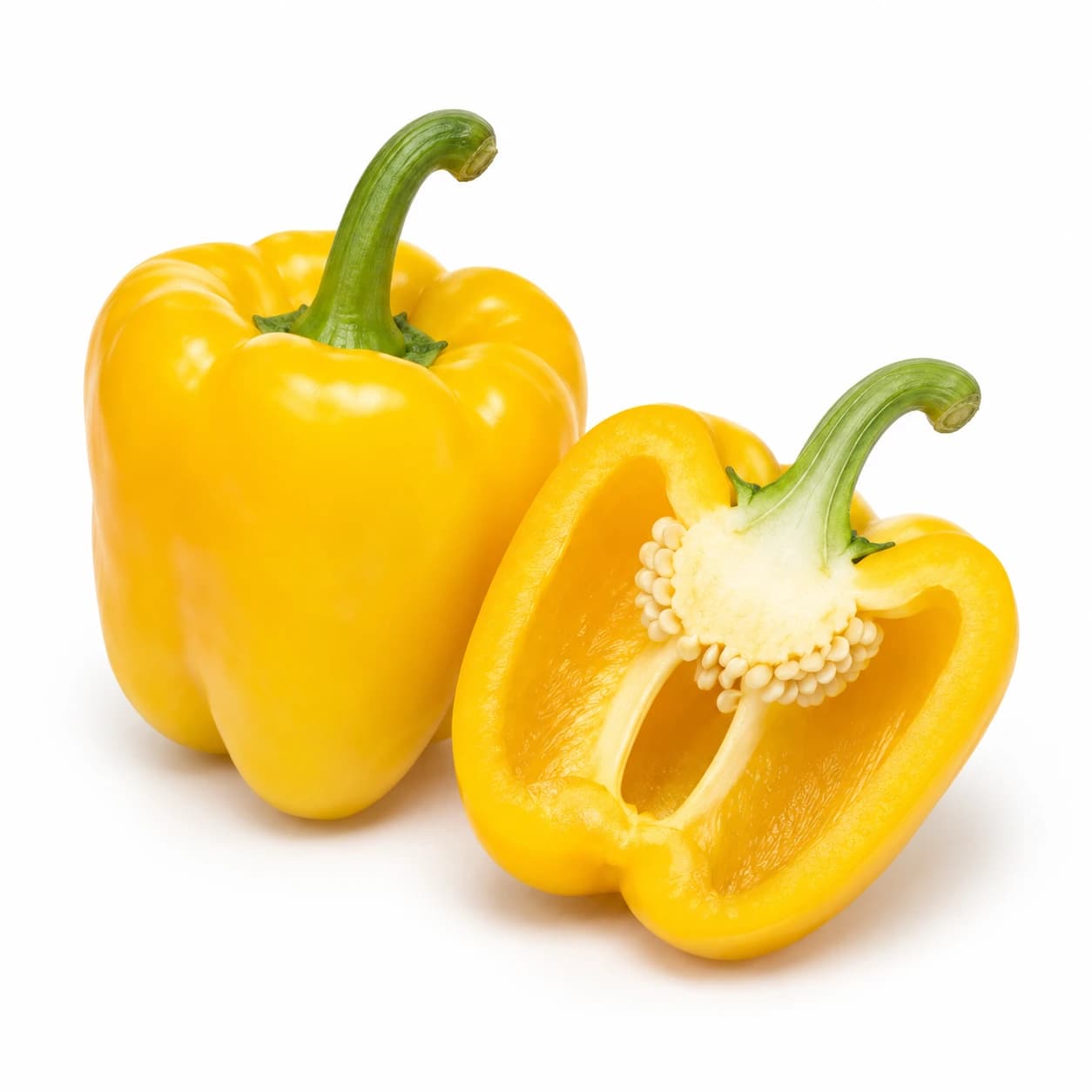 Cela rumena paprika z zelenim pecljem in prerezana polovica z vidnimi semeni.